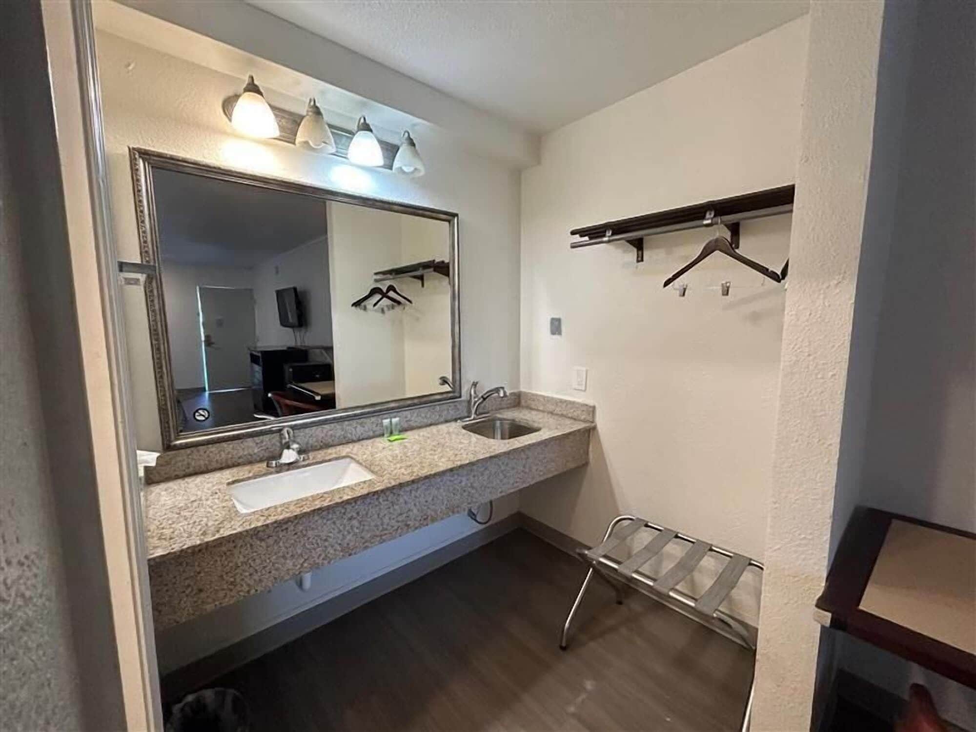 A bathroom with a large mirror, two sinks, a towel rack, and a shower area.