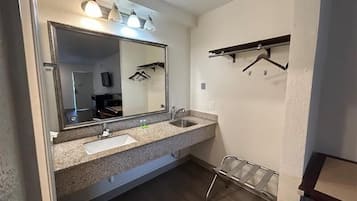 A bathroom with a large mirror, two sinks, a towel rack, and a shower area.