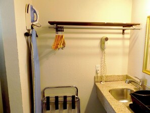 A bathroom with a sink, a towel rack, a hairdryer, and a towel hanging on a rack. - Studio 6 Fort Worth, TX – Downtown East (Fort Worth)