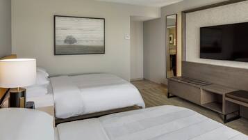 Une chambre d’hôtel avec deux lits, une télévision, un bureau et une grande fenêtre.