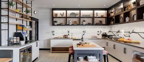 A modern kitchen with a central island, built-in shelves, and a coffee machine.