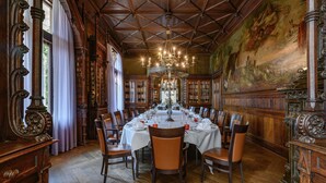 A dining room with a large round table set for a meal, surrounded by chairs.