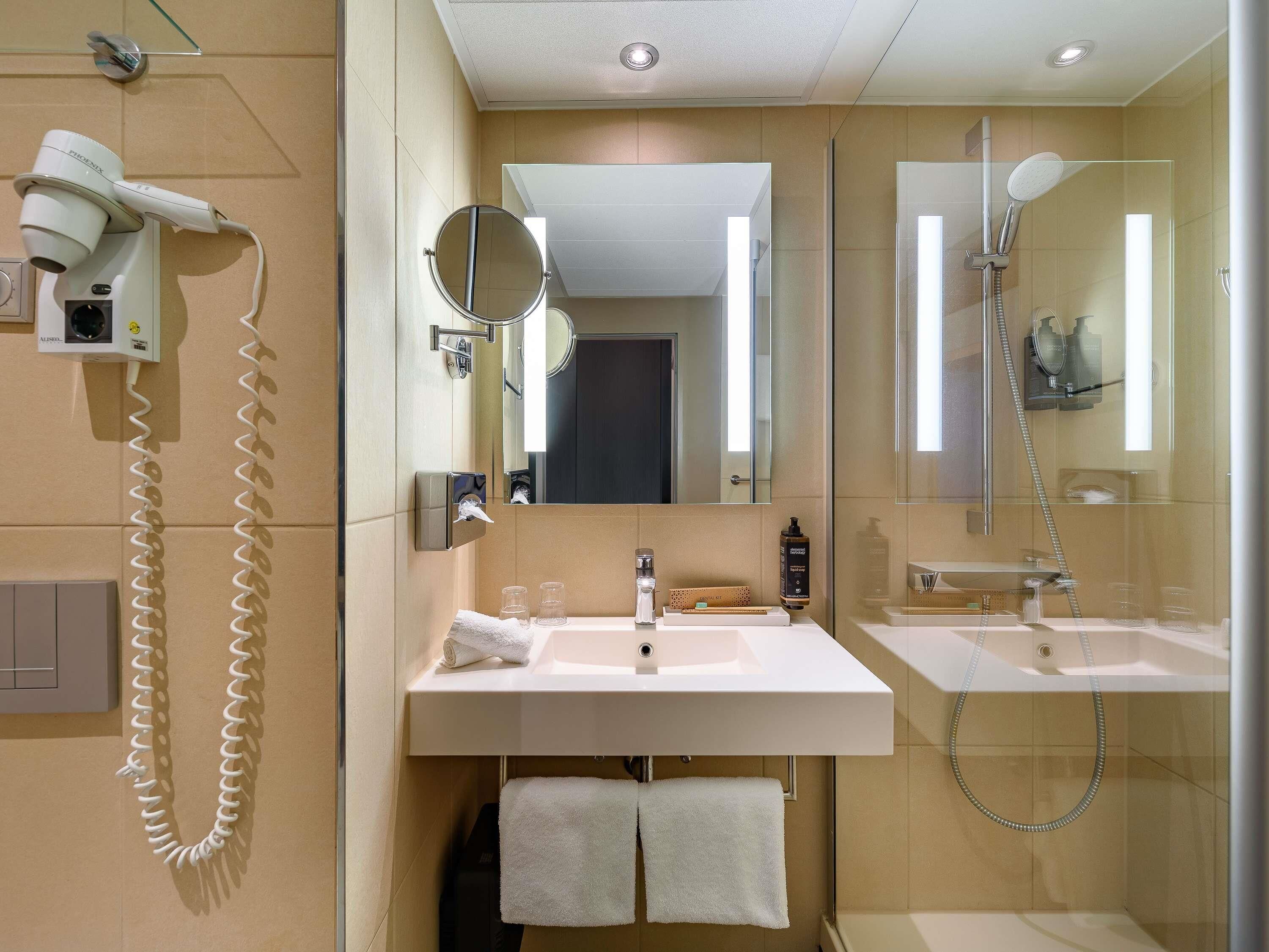 Un baño con dos lavamanos, un secador de pelo, un espejo y una ducha.