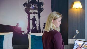 A hotel room with a bed, a laptop, and a wall with a silhouette of a person.