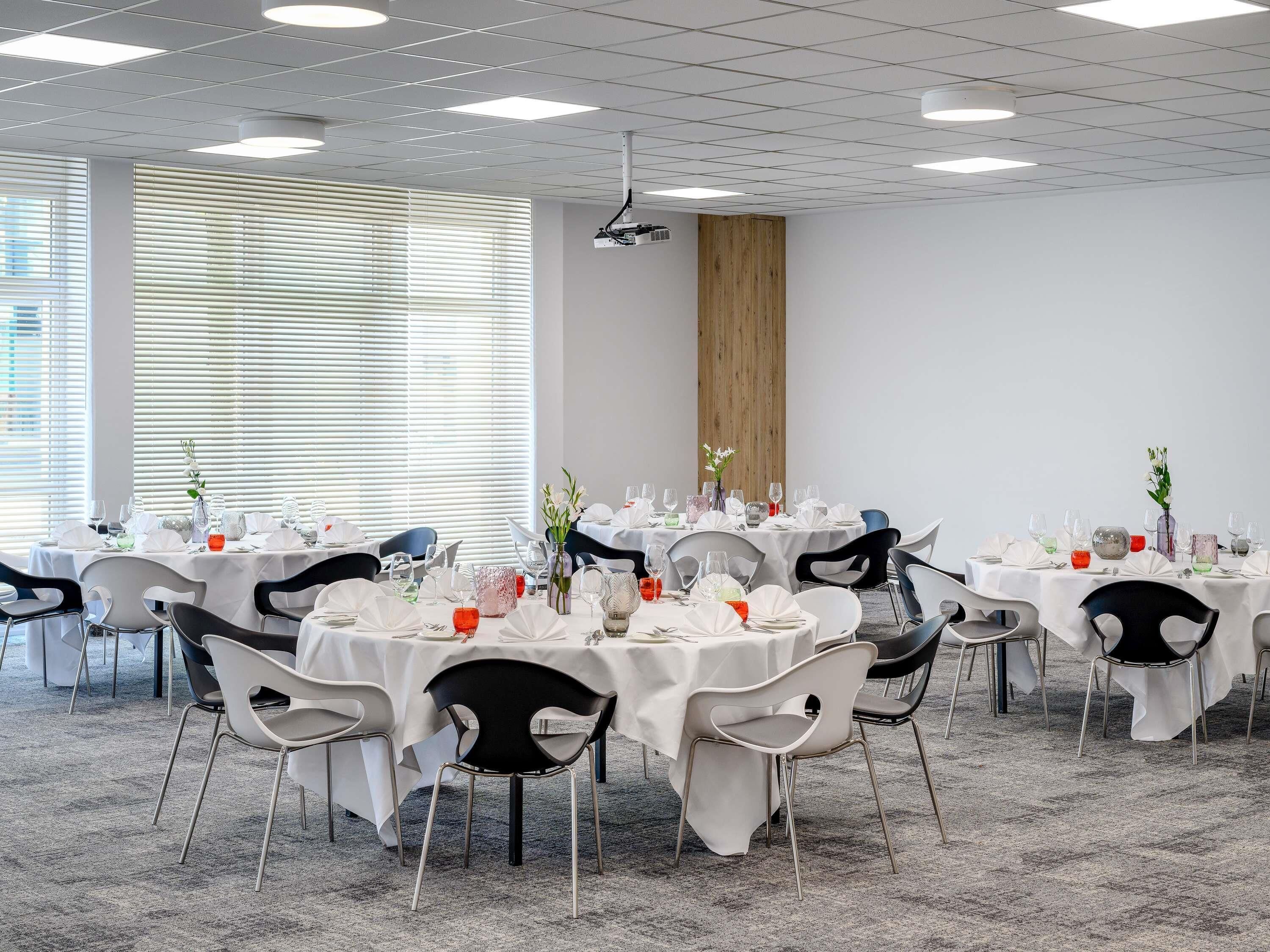 A conference room with round tables, chairs, and a projector.