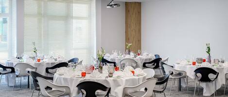 A conference room with round tables, chairs, and a projector.