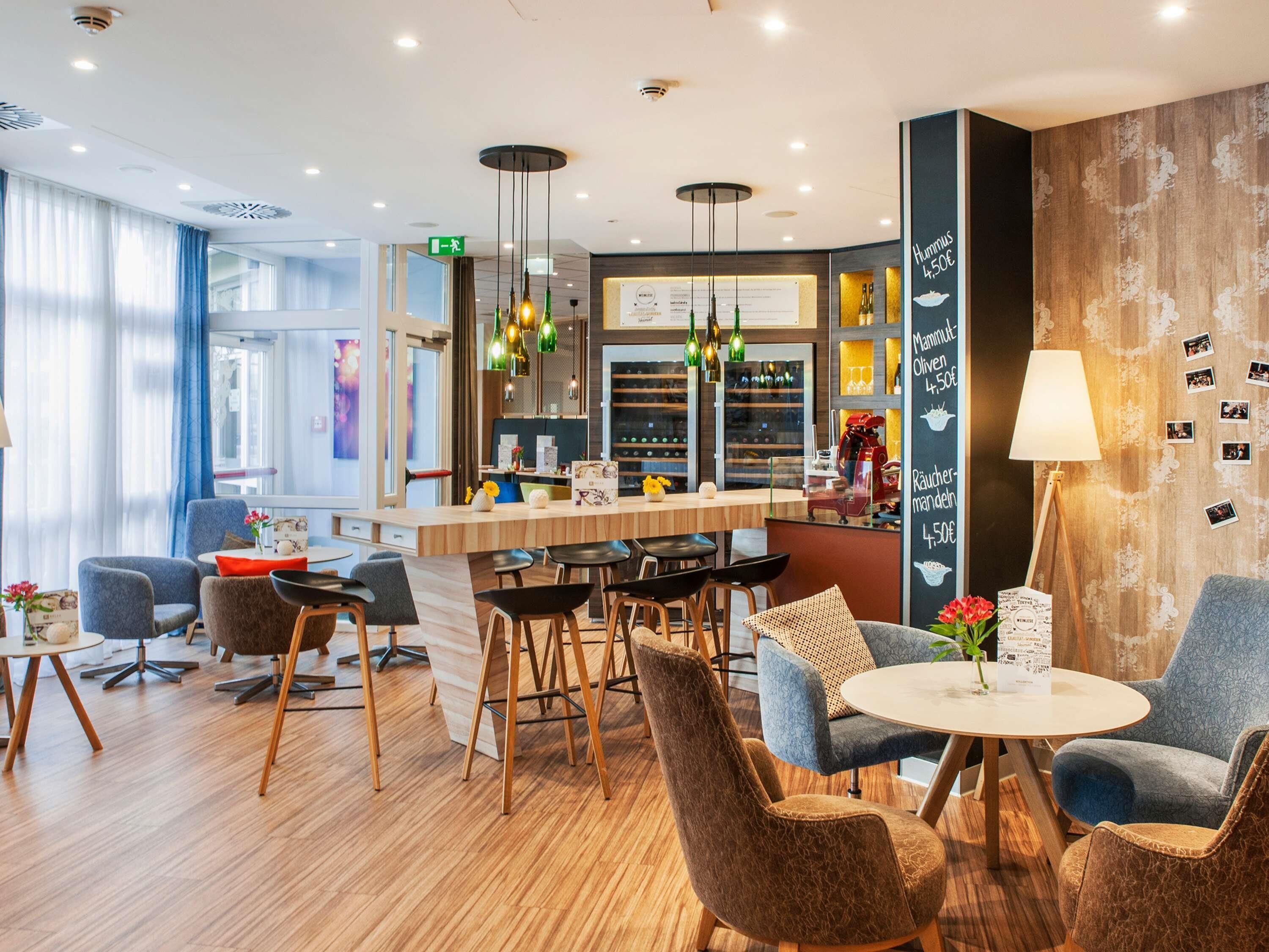 A modern hotel lobby with a bar area, seating arrangements, and a decorative wall with menu items.