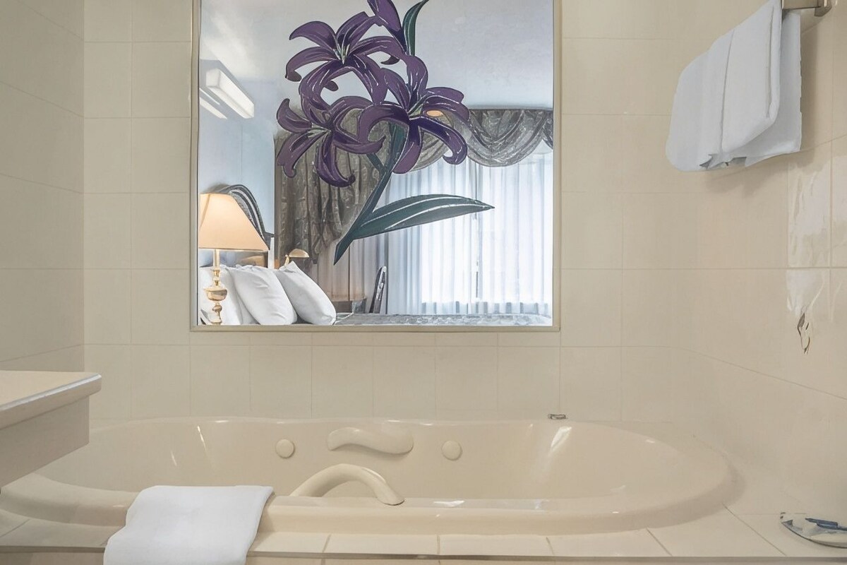 A bathroom with a bathtub, a mirror, and a towel rack.