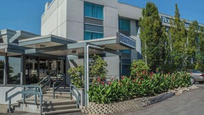 A modern building with a registration sign, a covered entrance, and a car parked nearby. - Rodeway Inn Fallsview (Niagara Falls)