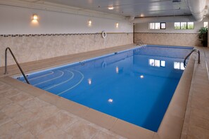 An indoor swimming pool with clear water, tiled walls, and a lifebuoy on the wall.