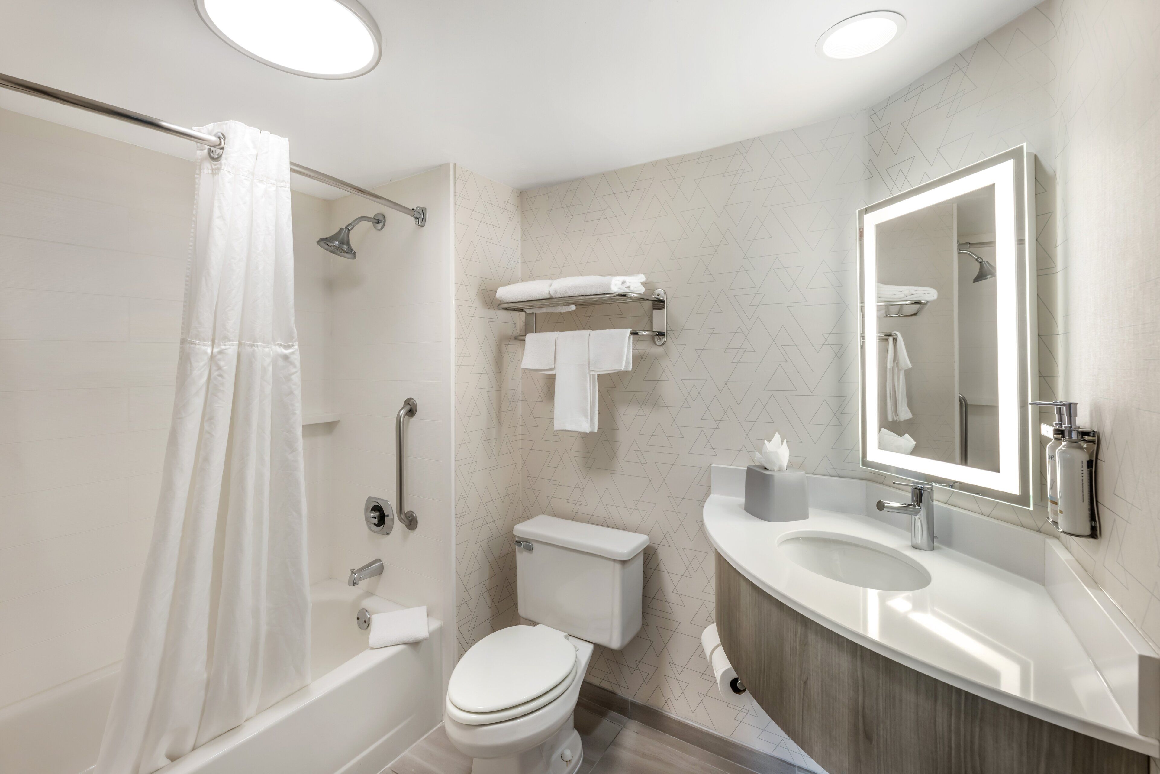 Un bagno moderno con doccia, wc, lavandino e specchio.