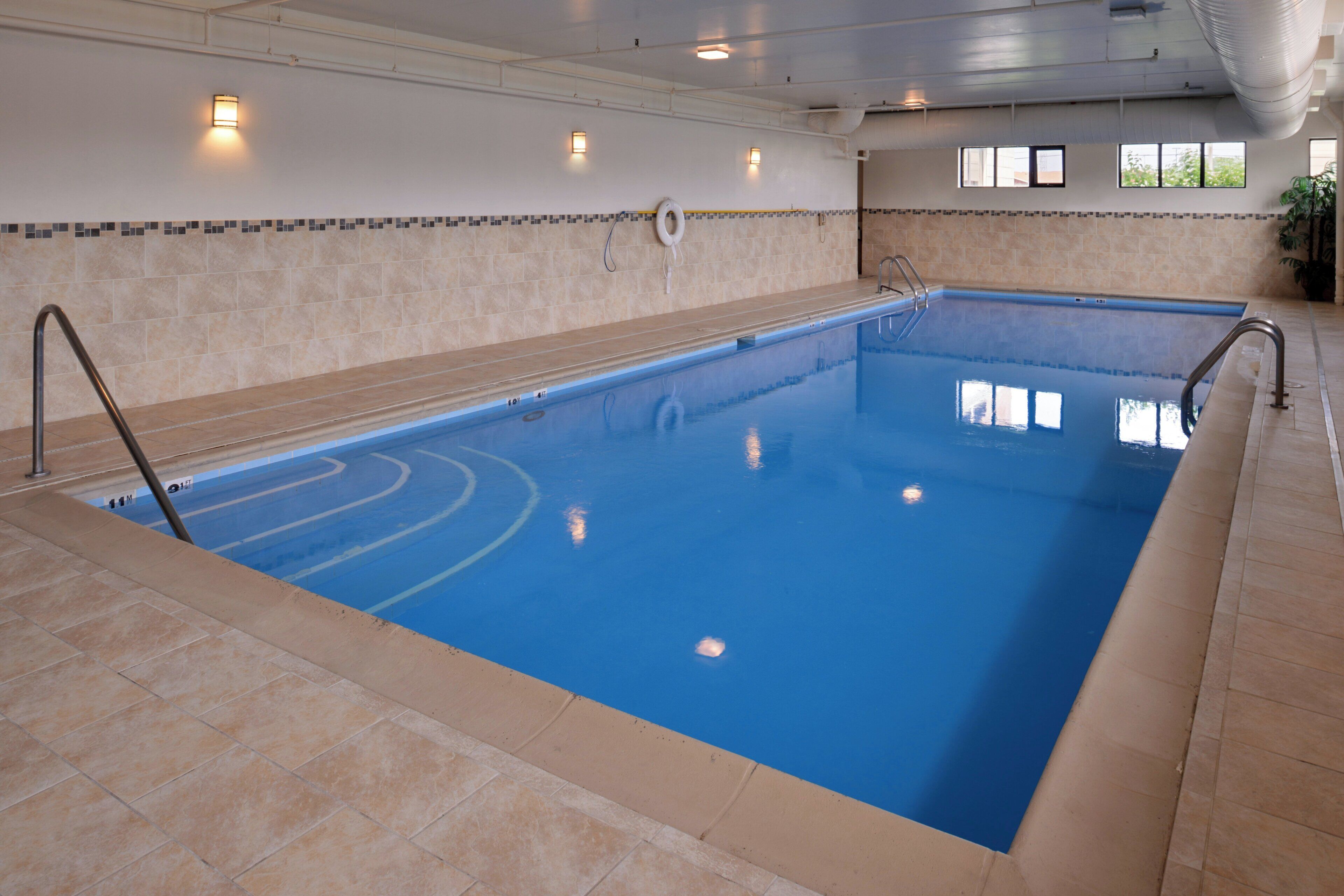 A large indoor swimming pool with clear blue water, tiled walls, and a tiled floor.