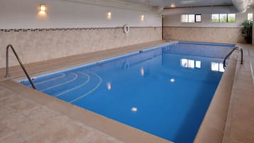 A large indoor swimming pool with clear blue water, tiled walls, and a tiled floor.
