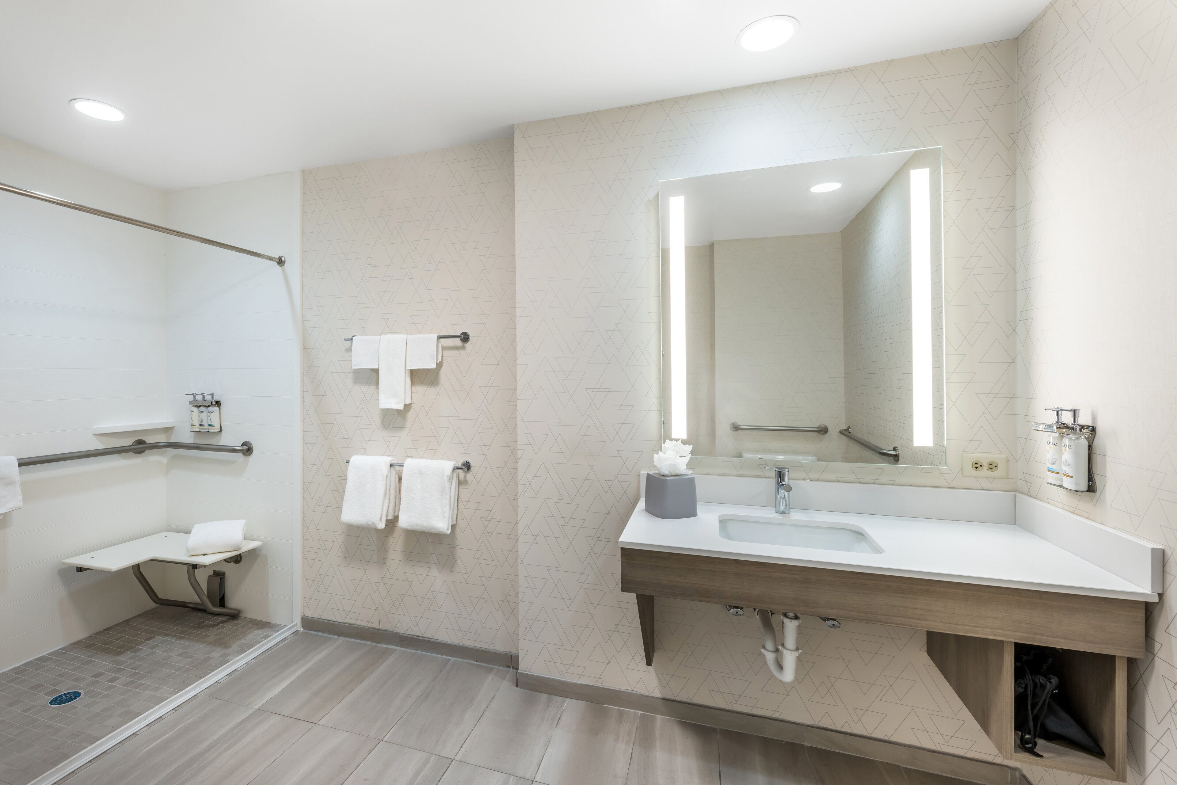 Un baño moderno con ducha, tocador con espejo y un perchero para toallas.