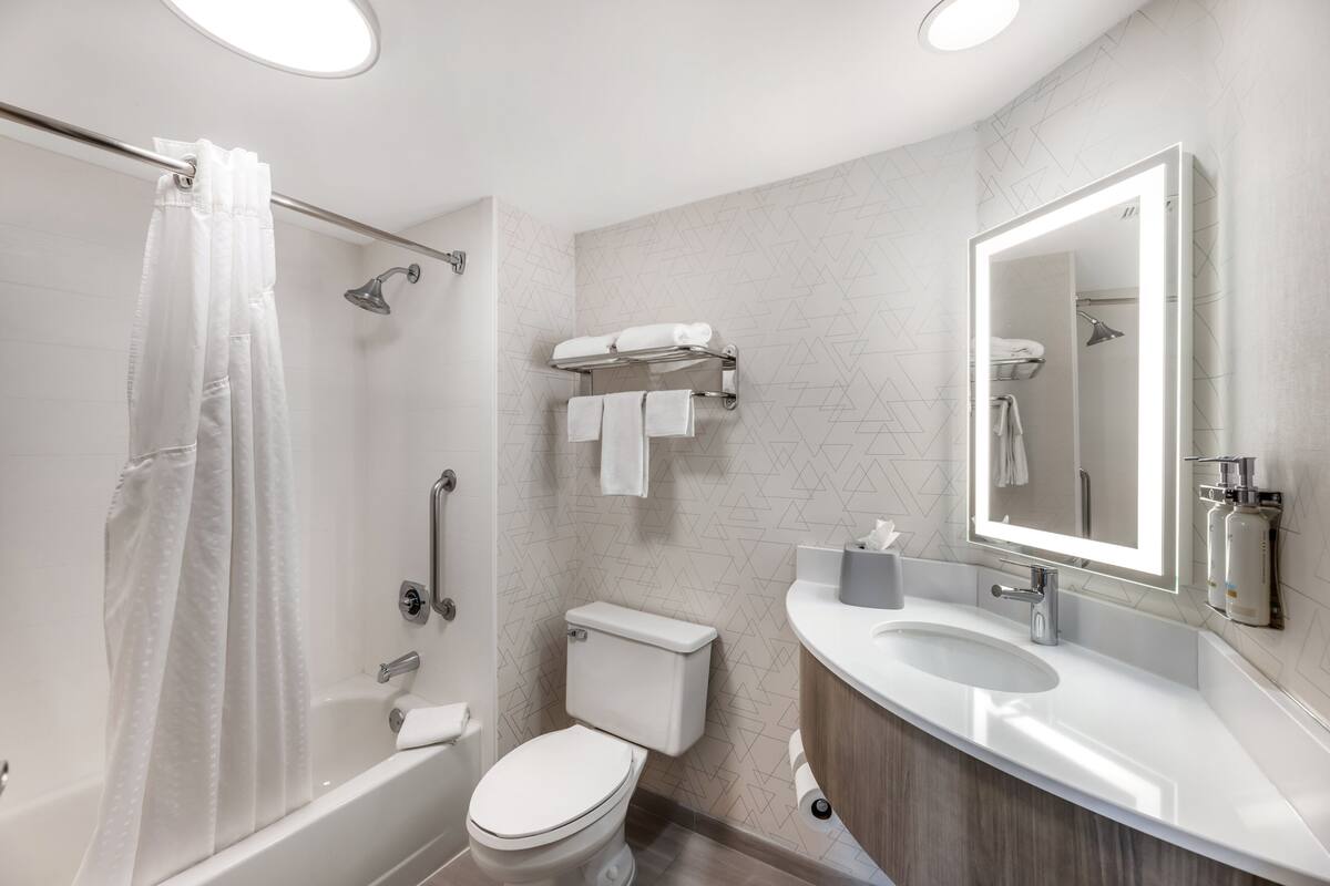 A modern bathroom with a shower, toilet, sink, and mirror.