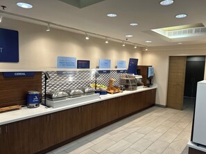 A breakfast bar with labeled sections for cereal, hot food, fruit, and bakery items.