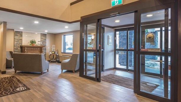 A lobby with a reception desk, seating area, and glass doors leading outside. - Comfort Inn (Chilliwack)
