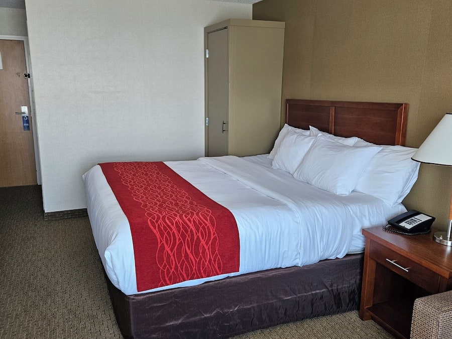 A hotel room with a bed, a desk, a chair, a lamp, and a telephone.