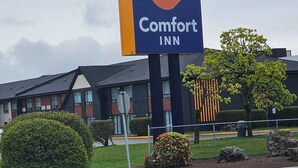 A Comfort Inn sign with a crescent logo, a modern building with a sloped roof, and well-maintained landscaping. - Comfort Inn (Chilliwack)