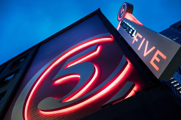 A hotel sign with a prominent red logo and the name "HOTEL FIVE" in white letters.