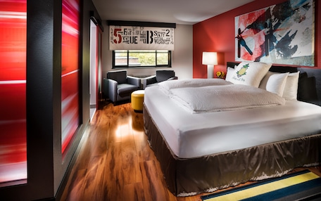 Una habitación de hotel moderna con una cama grande, un sofá, una mesita y una ventana con vistas.
