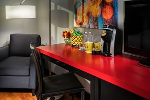 A red table with a coffee maker, a mug, and a vase with flowers.