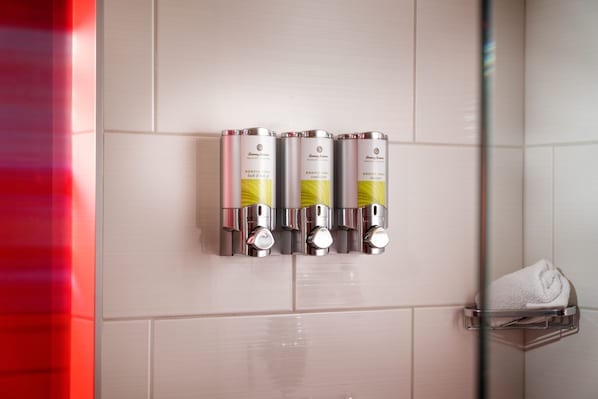 A bathroom with four bottles of bath and body products on a wall.