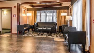 A hotel lobby with a sofa, armchairs, a coffee table, and a patterned rug.