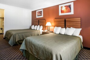 A hotel room with two beds, a nightstand with a lamp, and two framed pictures on the wall. - Quality Inn Rutland - Killington (Rutland)