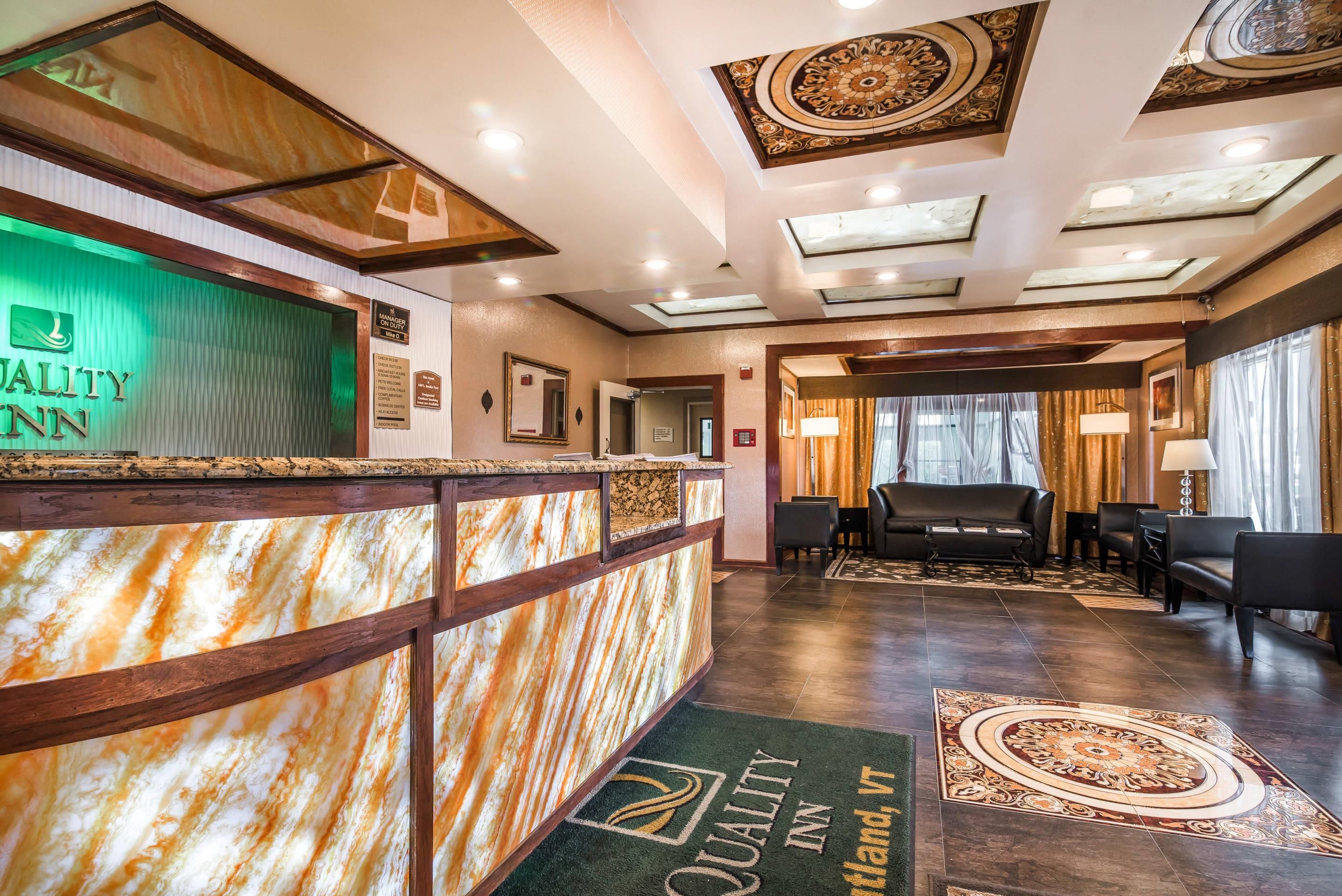 A hotel reception area with a marble counter, a green-lit sign, and a reception desk.
