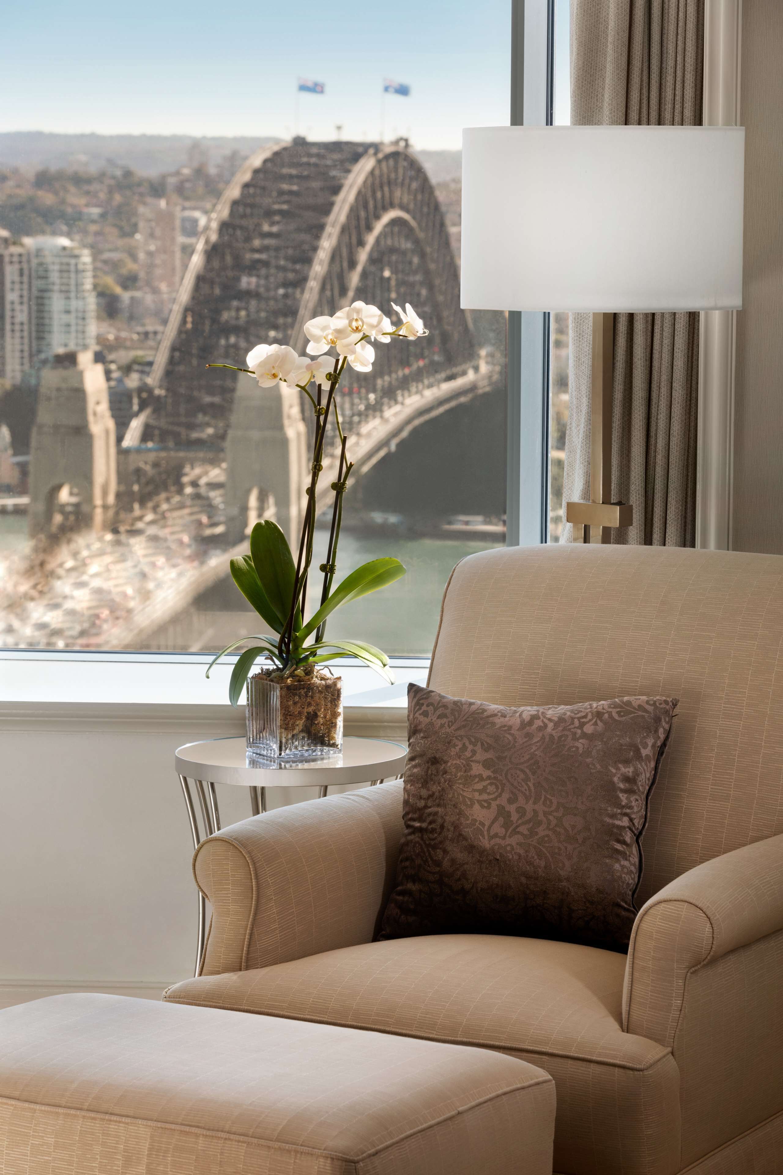 A room with a view of a bridge, a sofa, a lamp, and a potted plant.