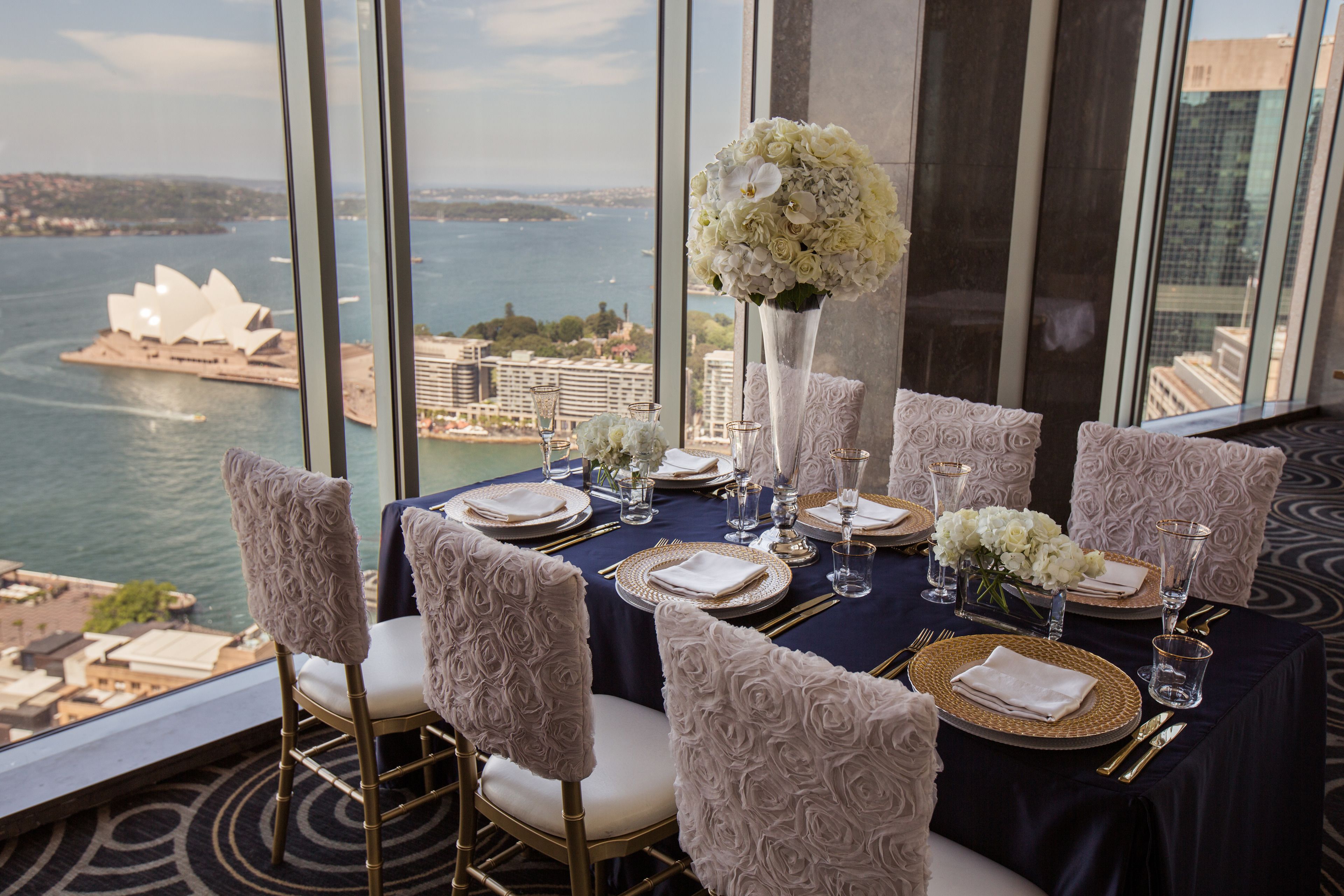 A table set for six with a view of the Sydney Opera House.