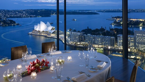 A table set for dinner with a view of a cityscape and a body of water. - Shangri-La Sydney (The Rocks)