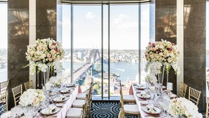 A table set for a formal event with a city view, including a bridge and buildings. - Shangri-La Sydney (The Rocks)