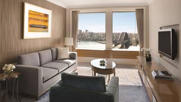 Ett modernt hotellrum med en soffa, ett soffbord, en TV och ett stort fönster med utsikt över staden.