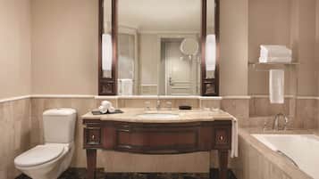 A bathroom with a marble sink, a toilet, a bathtub, and a large mirror.
