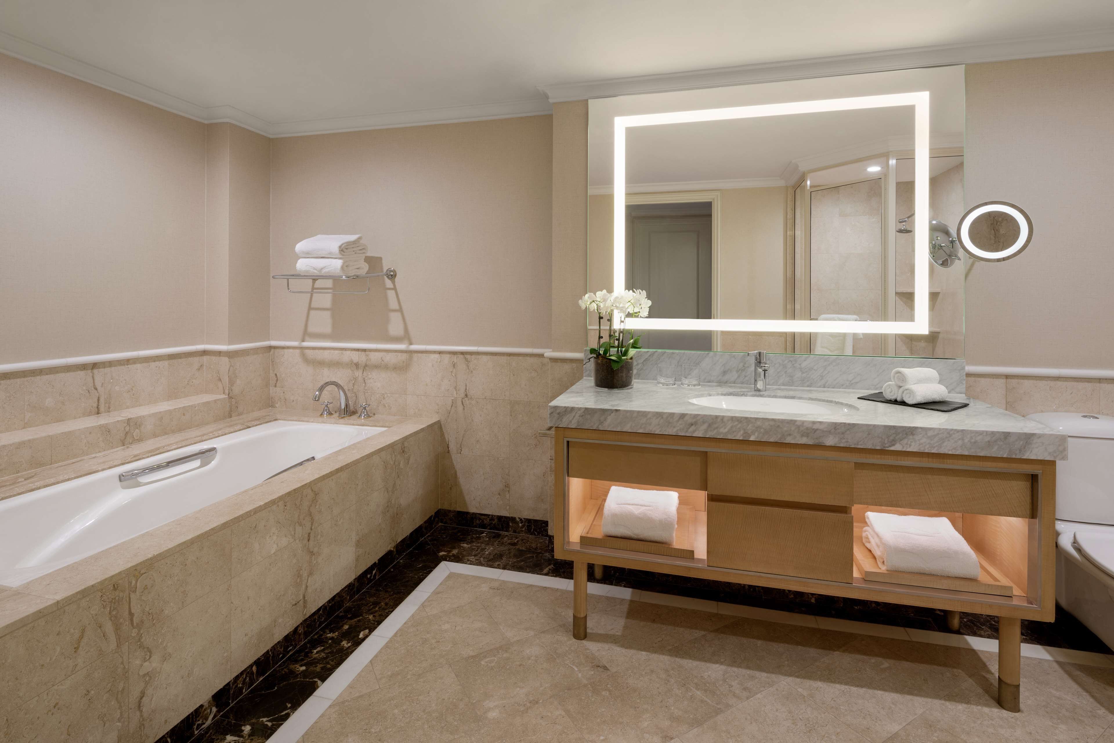 Ein modernes Badezimmer mit einer großen Badewanne, einem Waschtisch mit Spiegel und einer Duschkabine.