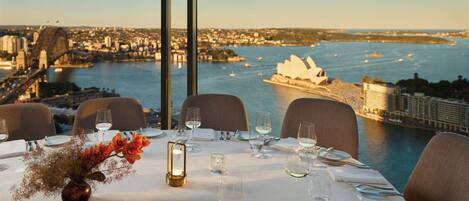 A table set for dining with a view of a cityscape and a bridge.