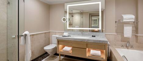 A modern bathroom with a glass shower enclosure, a large mirror, a vanity with a sink, and a bathtub.