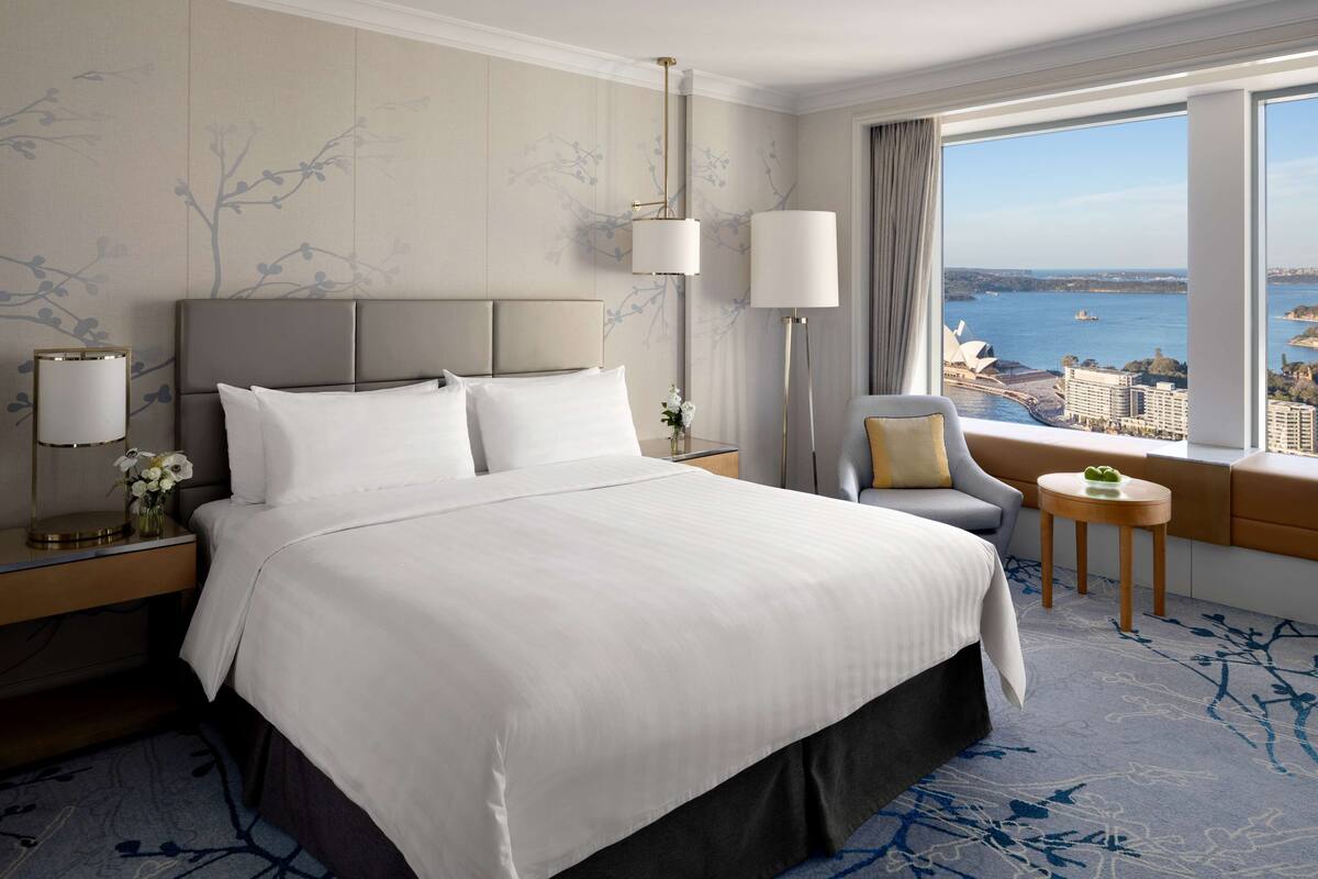A hotel room with a large bed, a seating area with a view of the city, and a large window.