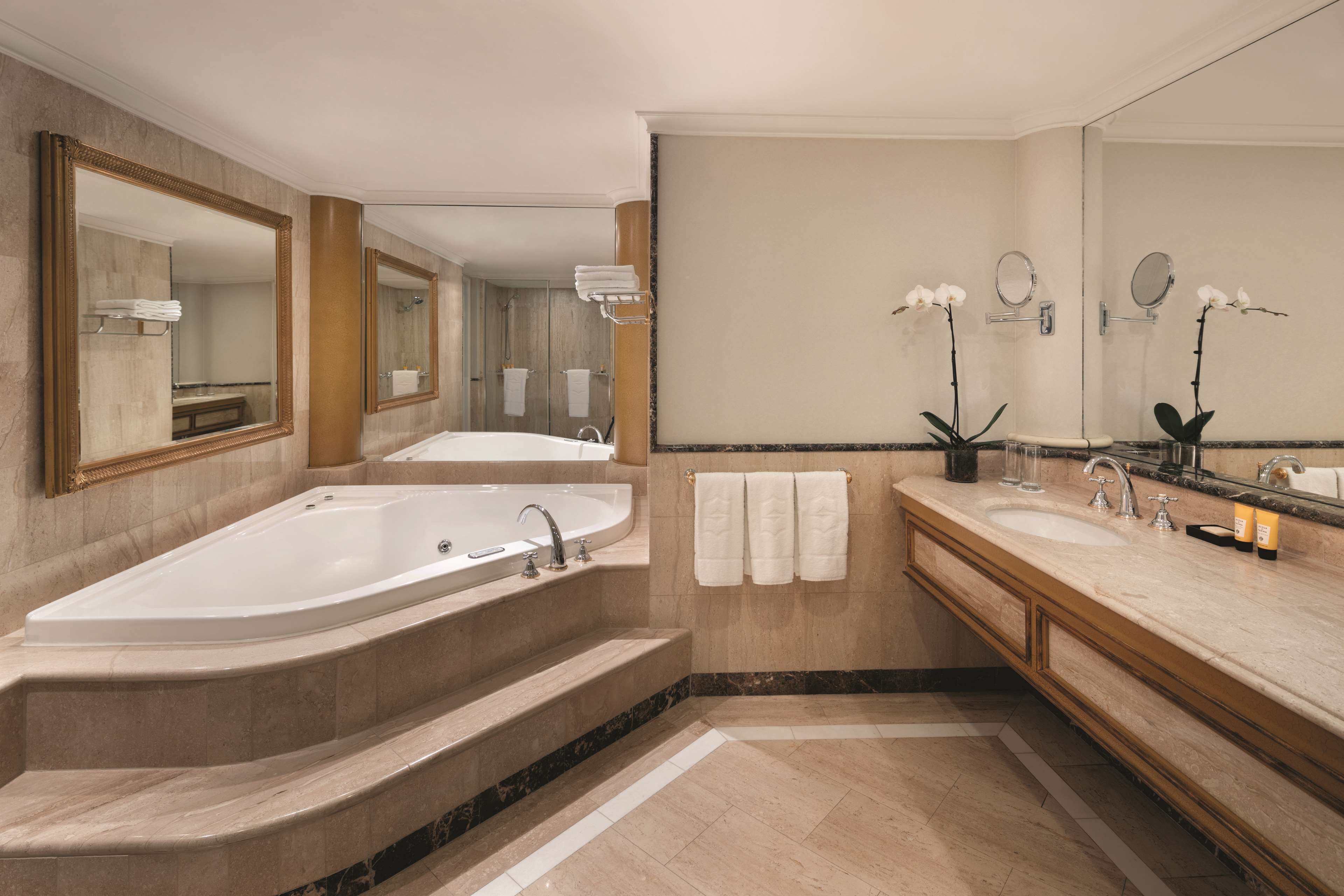 A modern bathroom with a large bathtub, two sinks, and multiple mirrors.