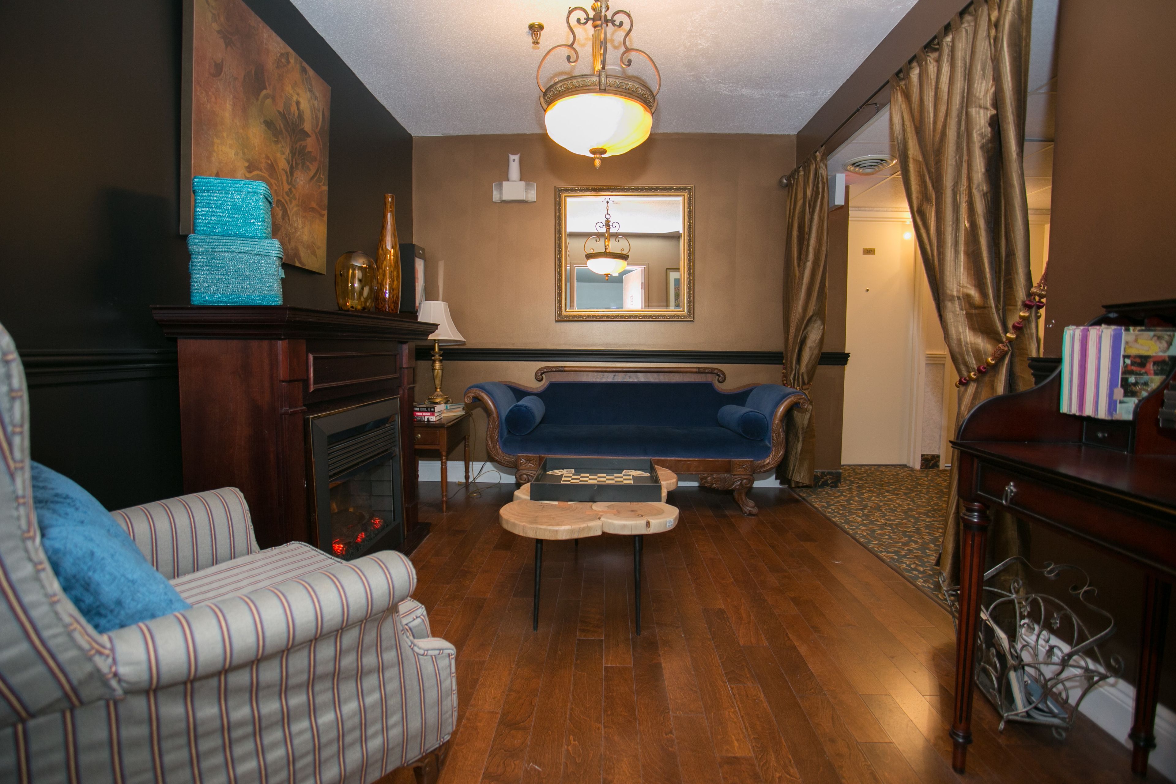 A room with a fireplace, a blue sofa, a striped armchair, and a wooden coffee table.