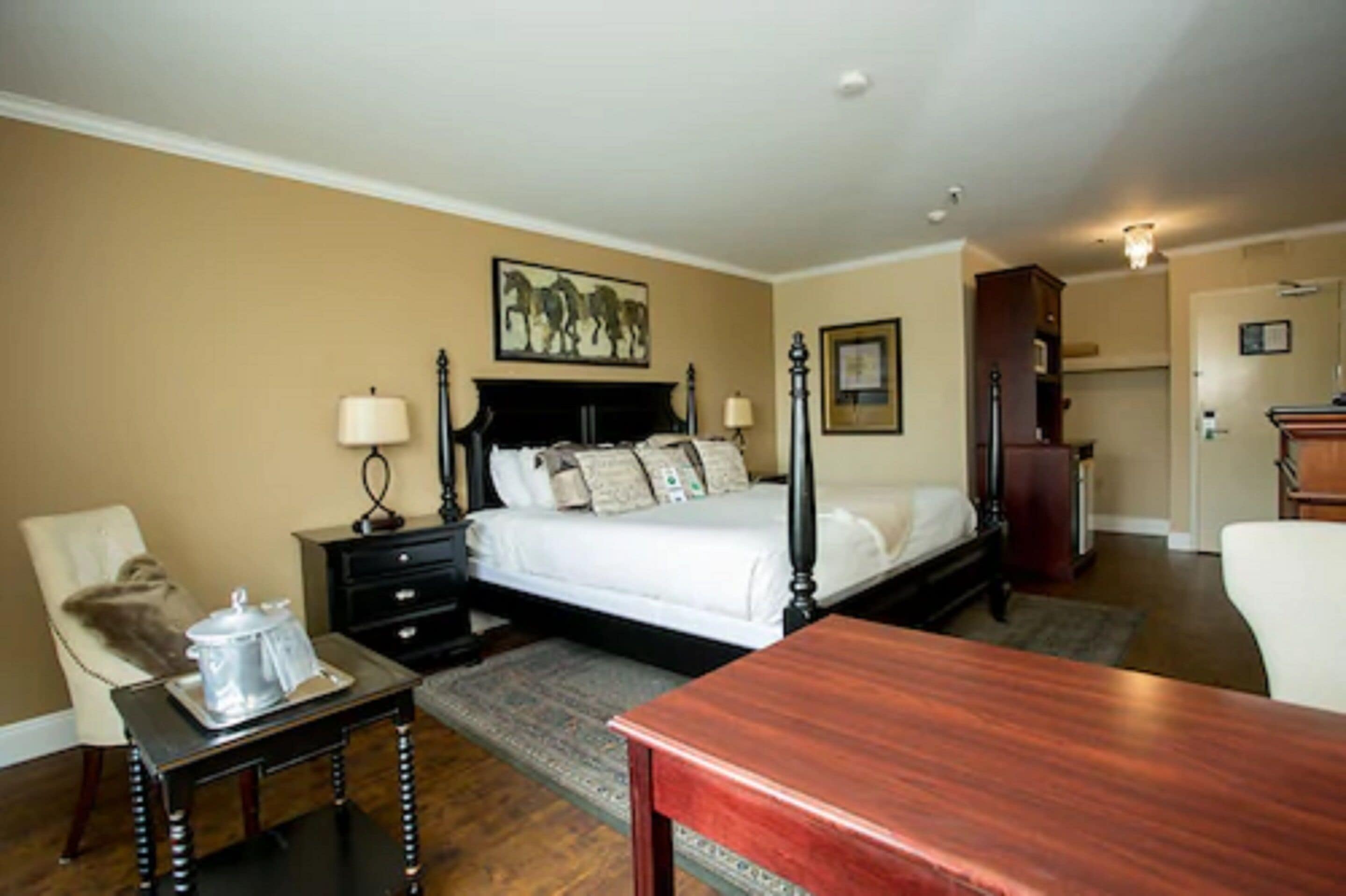 Une chambre à coucher avec un lit à baldaquin, une table de chevet, une chaise, une table en bois et un tableau accroché au mur.
