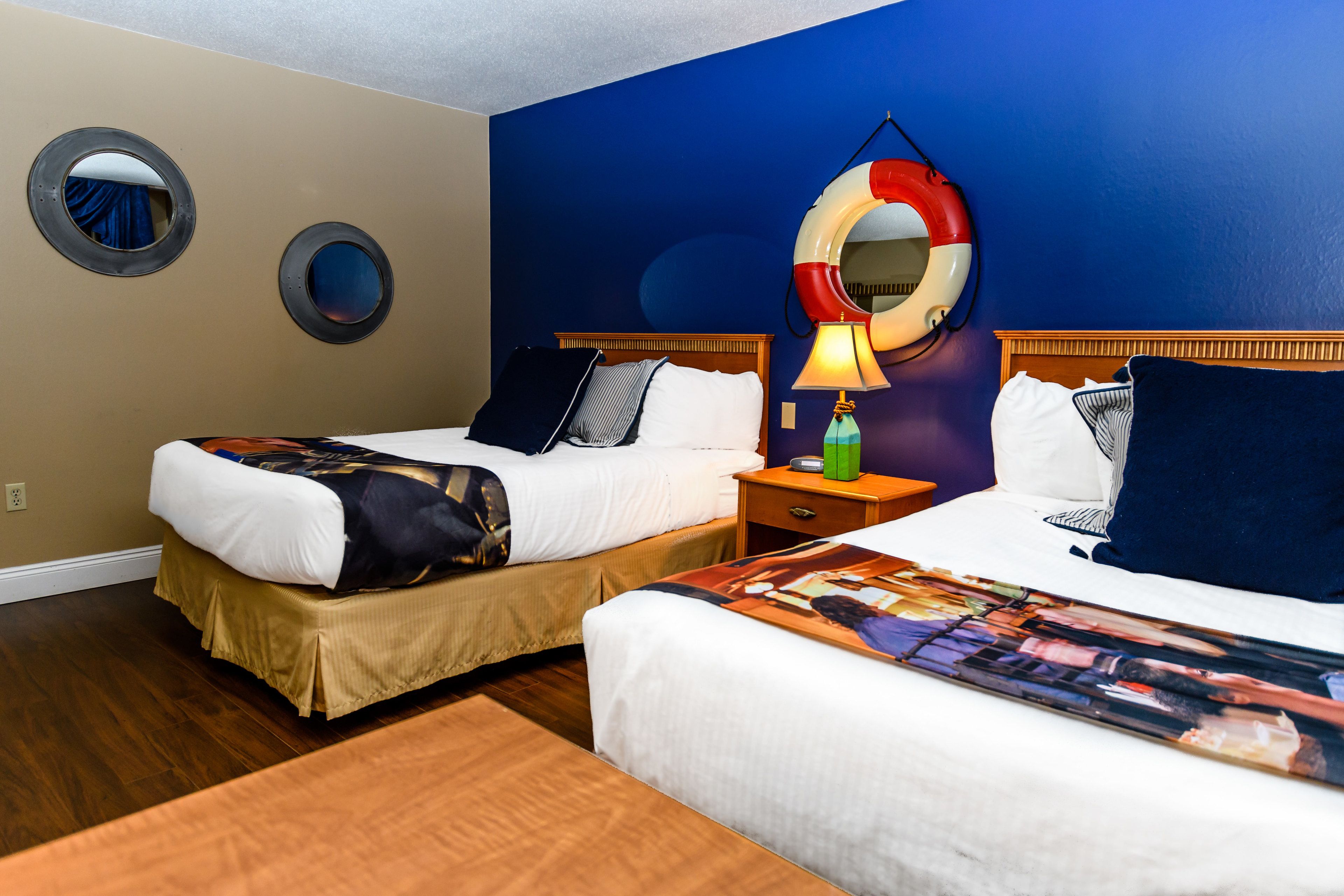 Ein Hotelzimmer mit zwei Betten, einem hölzernen Kopfteil, einem Nachttisch mit Lampe und einem großen runden Spiegel an der Wand.