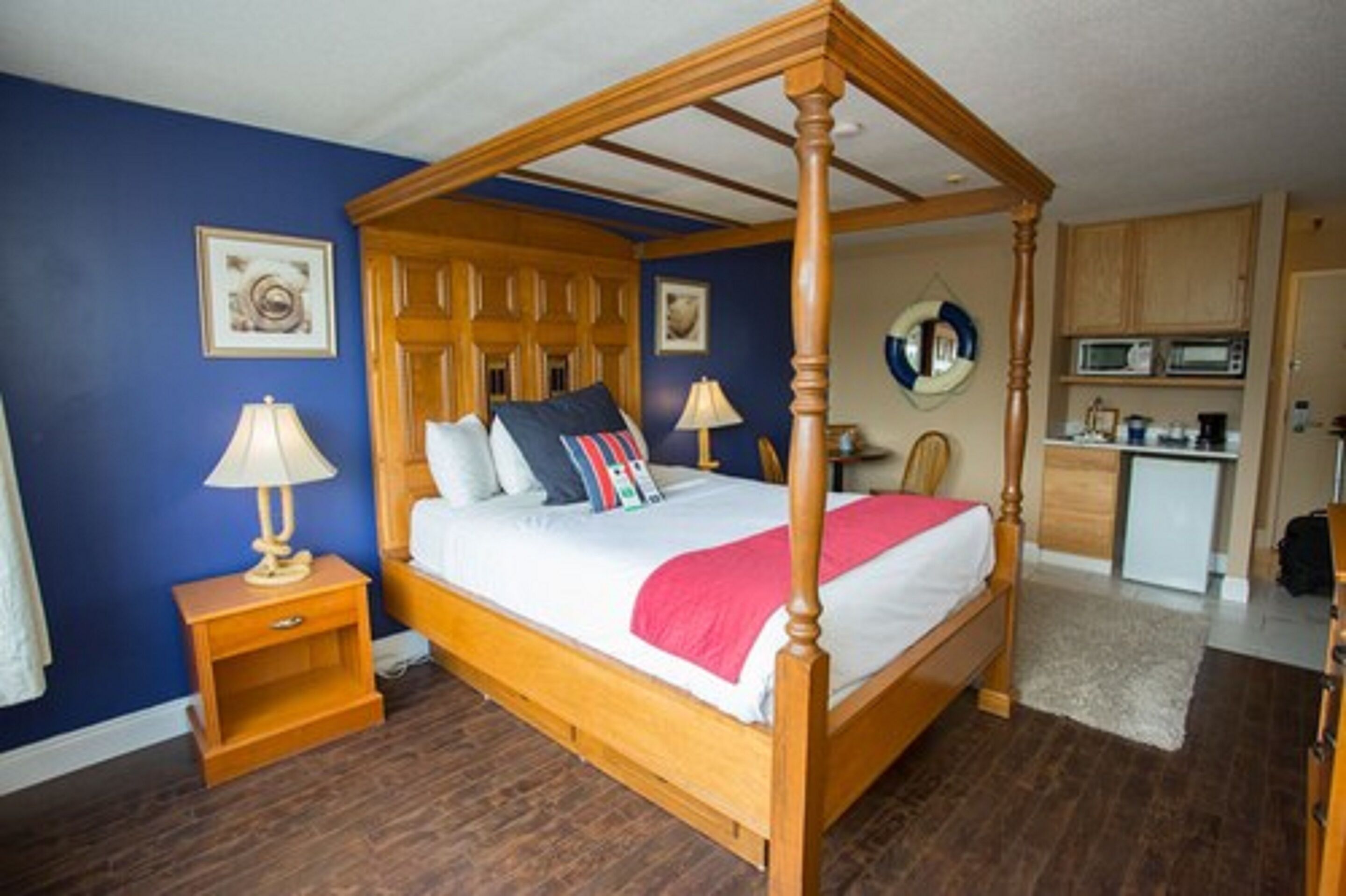 A four-poster bed with a wooden frame, a bedside table with a lamp, and a small cabinet.