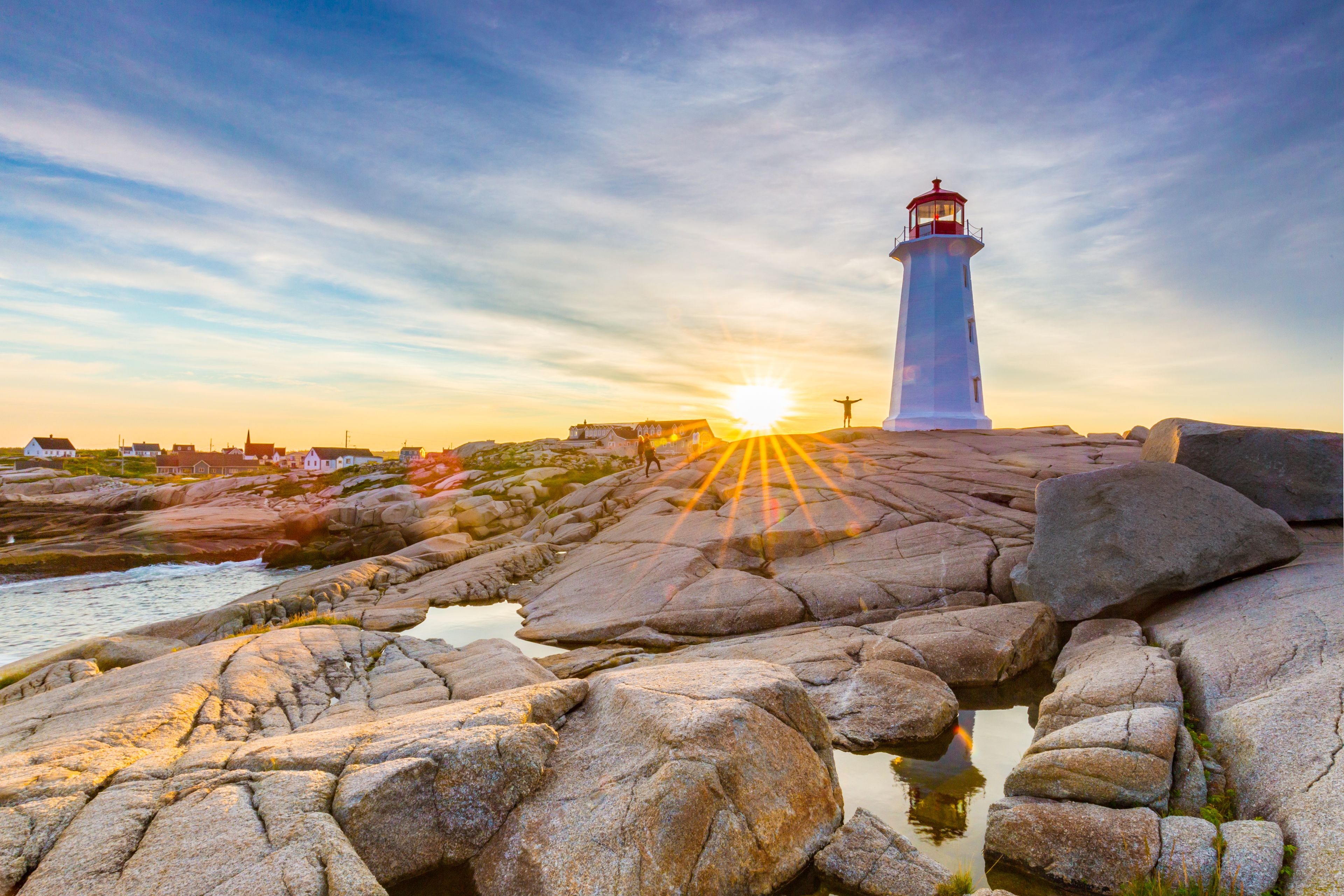 Un phare sur une côte rocheuse, avec le soleil couchant en arrière-plan.