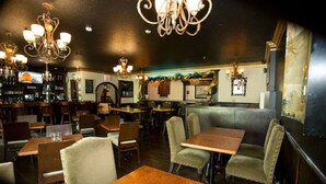 Un interior de restaurante con mesas y cabinas de madera, candelabros y una zona de bar.