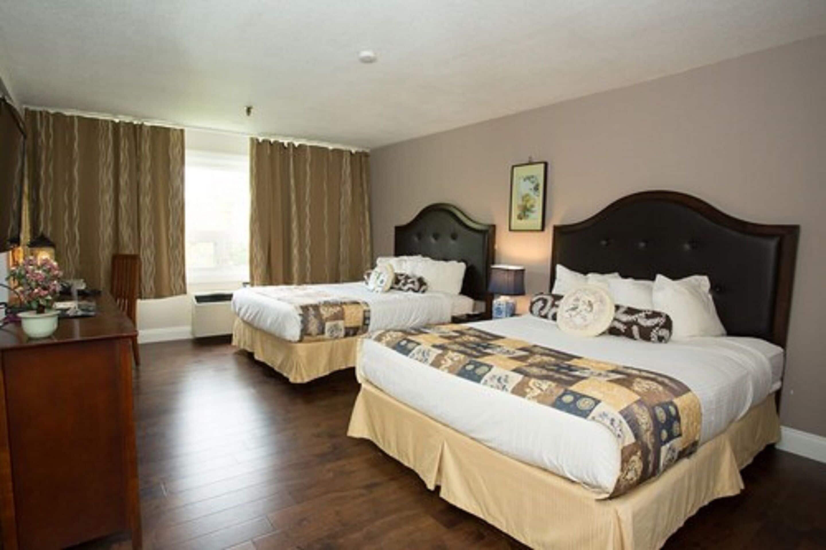 Habitación de hotel con dos camas, un escritorio y una ventana con cortinas.