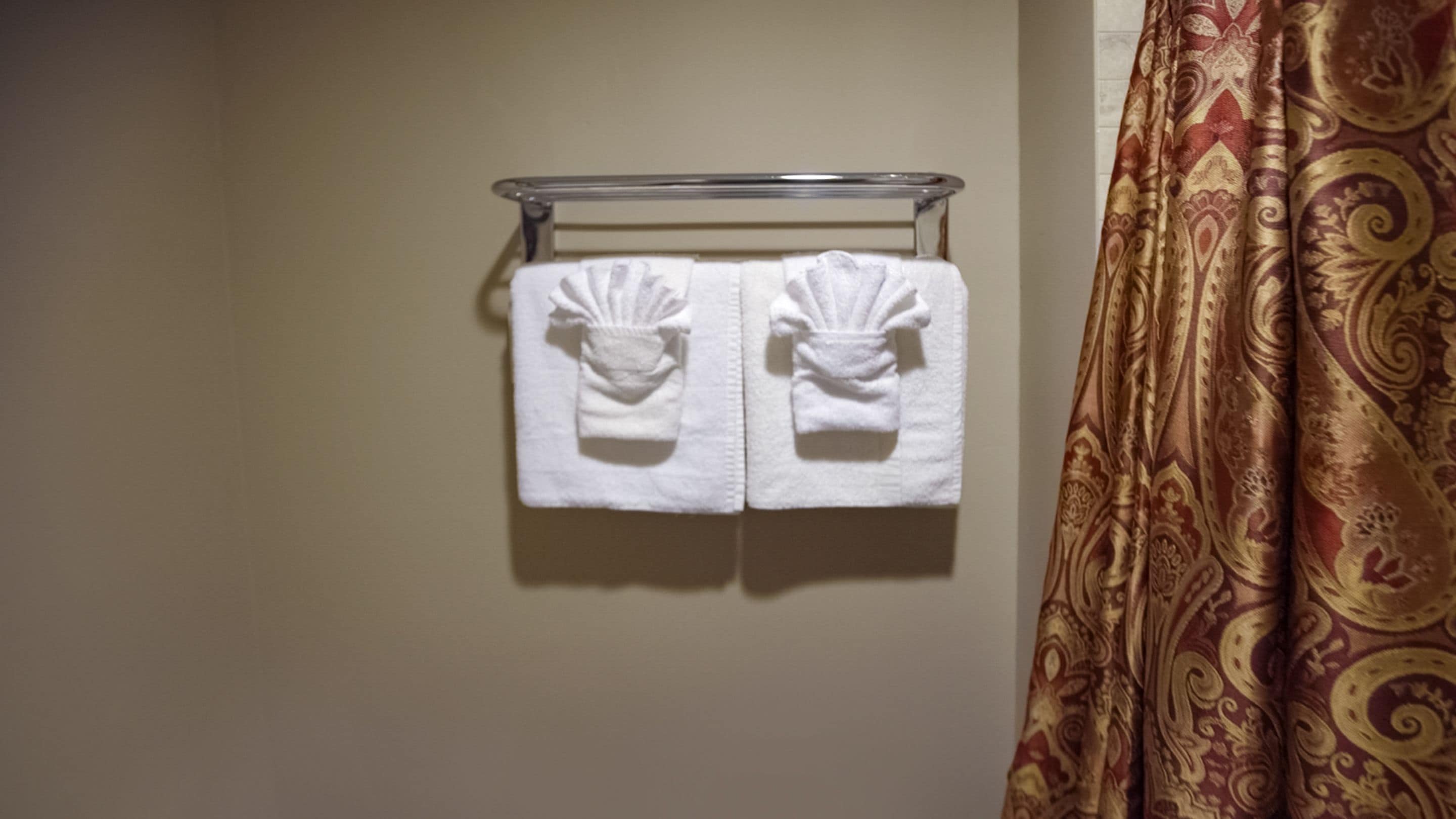 Un baño con un perchero que sostiene dos toallas blancas.