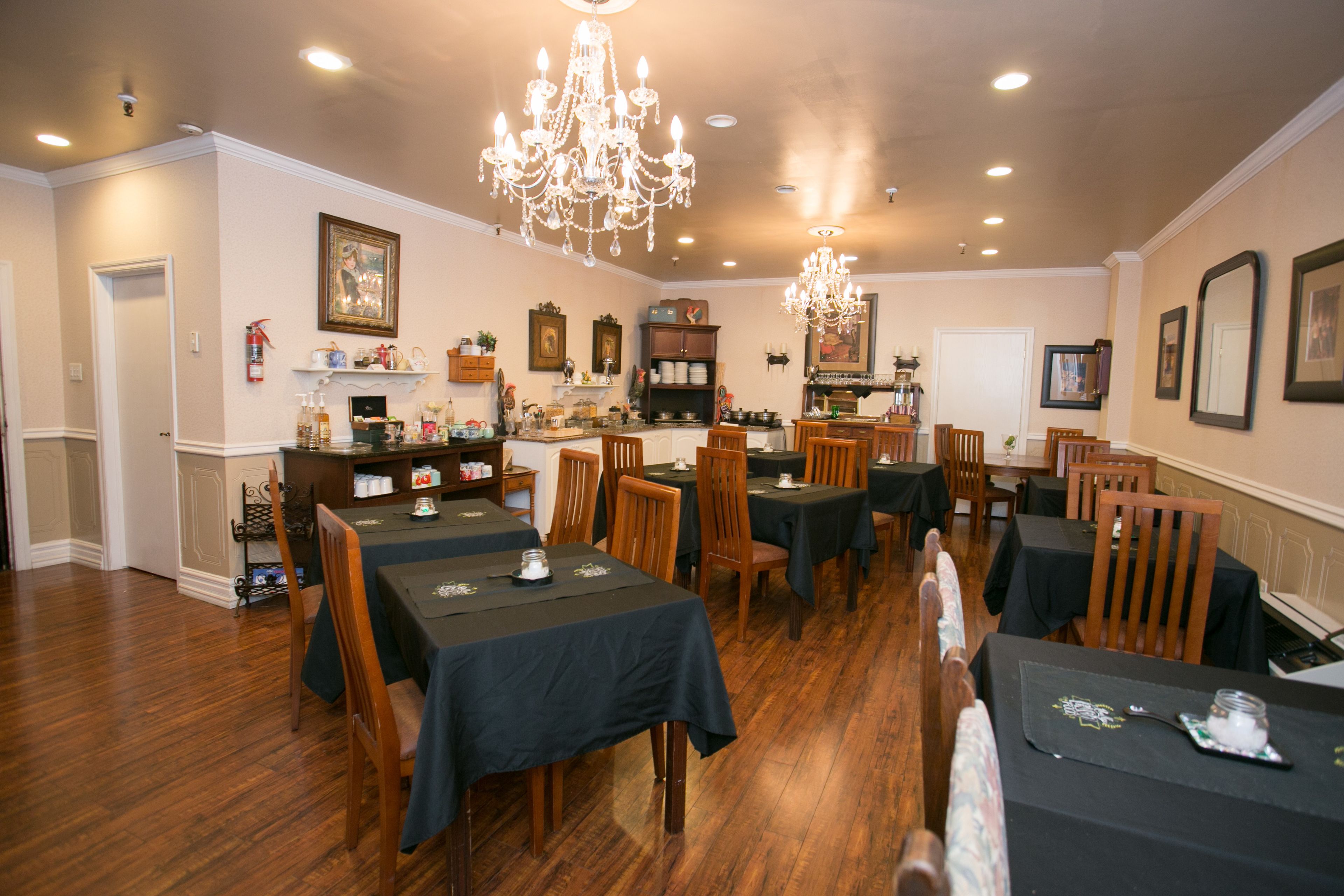 A dining area with multiple tables and chairs, a chandelier, and wall-mounted decorations.